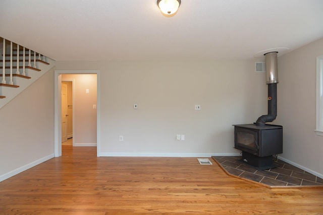 unfurnished living room with a wood stove and hardwood / wood-style floors