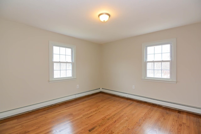 spare room with a baseboard heating unit, light hardwood / wood-style floors, and a healthy amount of sunlight