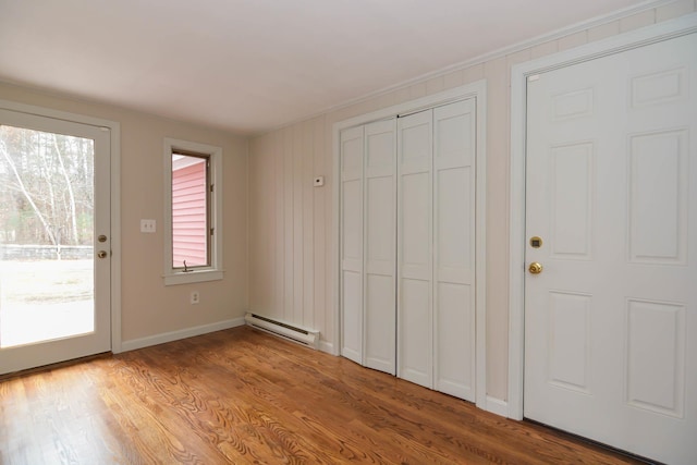 unfurnished bedroom with access to exterior, a baseboard radiator, and light hardwood / wood-style floors