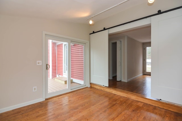 spare room featuring hardwood / wood-style floors, a barn door, and rail lighting