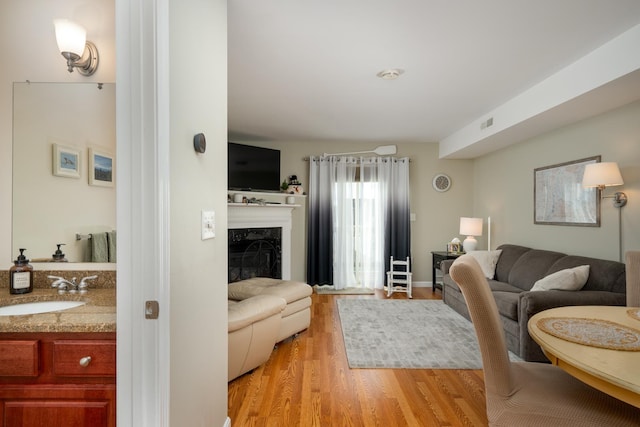 living room with light hardwood / wood-style floors, sink, and a high end fireplace