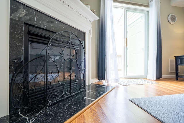 interior details with wood-type flooring and a high end fireplace