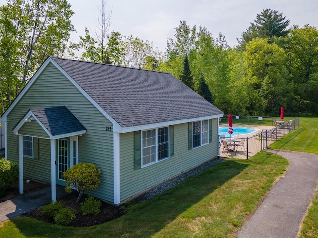 view of side of property featuring a lawn, a patio area, and a fenced in pool