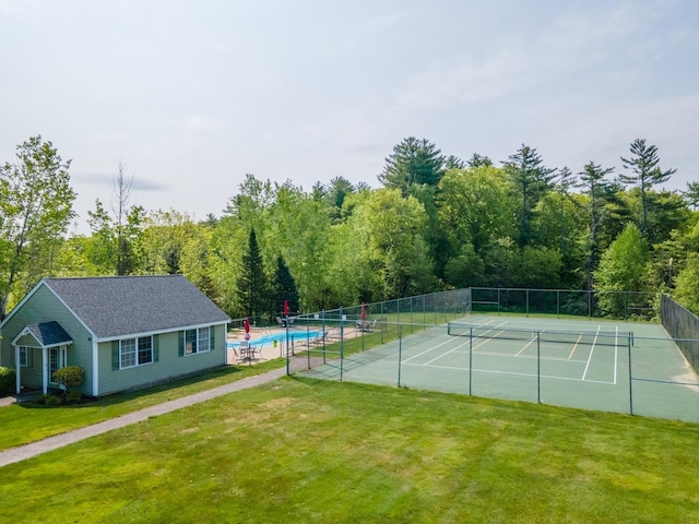 view of tennis court featuring a lawn