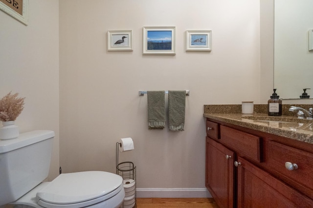 bathroom with hardwood / wood-style floors, vanity, and toilet