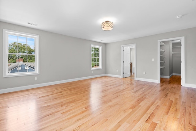 unfurnished bedroom featuring a spacious closet, light hardwood / wood-style flooring, and a closet