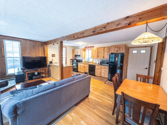 living room featuring beam ceiling, sink, light hardwood / wood-style flooring, a textured ceiling, and wooden walls