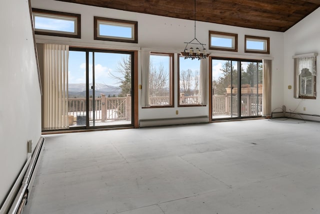 unfurnished room featuring a mountain view, a towering ceiling, a baseboard radiator, and a notable chandelier