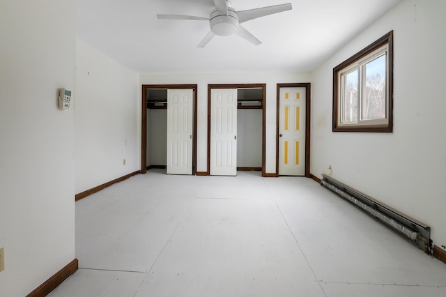 unfurnished bedroom with ceiling fan, a baseboard heating unit, and two closets