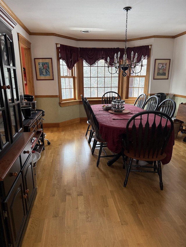 dining area featuring crown molding, light hardwood / wood-style floors, and a chandelier