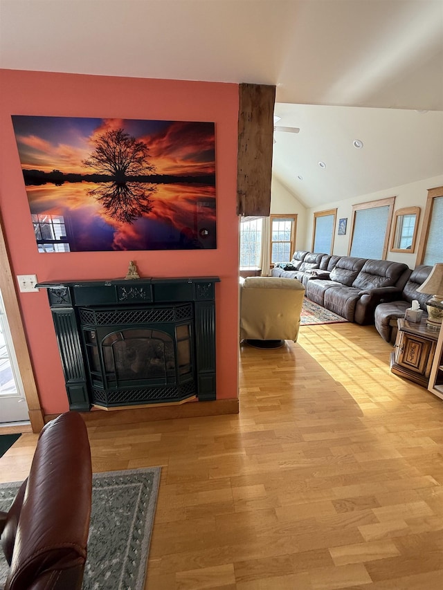 living room with a tiled fireplace, vaulted ceiling, and hardwood / wood-style flooring