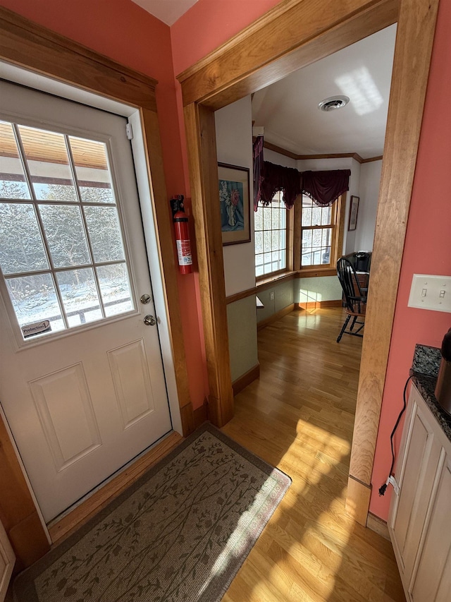 doorway featuring crown molding and light hardwood / wood-style floors