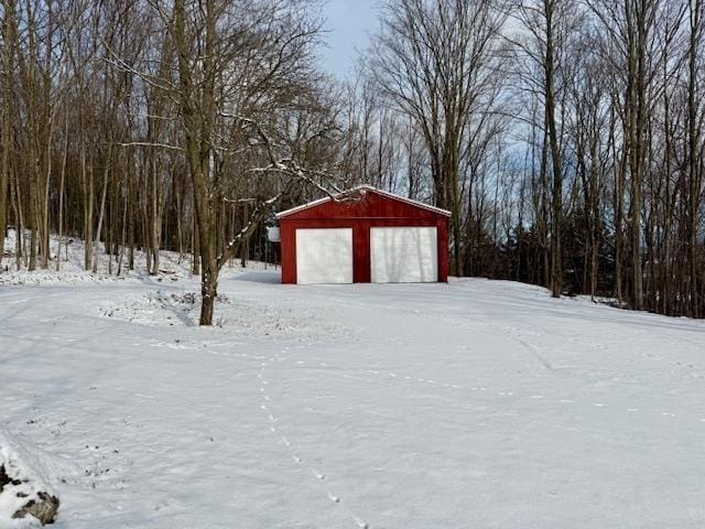 snowy yard featuring a garage and an outdoor structure