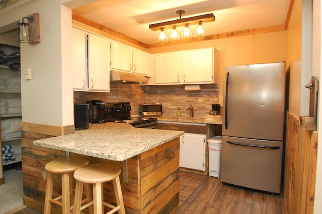 kitchen with backsplash, white cabinets, black range with electric cooktop, kitchen peninsula, and stainless steel refrigerator