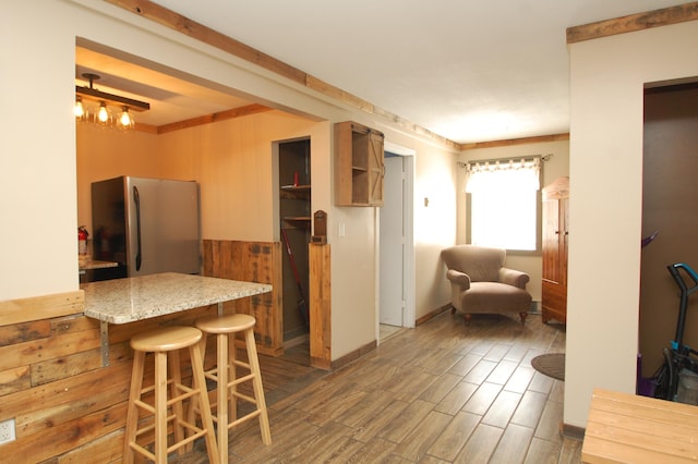 kitchen with a breakfast bar, stainless steel fridge, and wood-type flooring