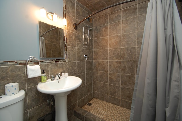 bathroom featuring a shower with shower curtain, toilet, and tile walls