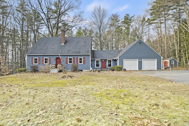 cape cod home with a front yard and a garage