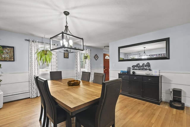 dining room with an inviting chandelier, a baseboard radiator, and light wood-type flooring