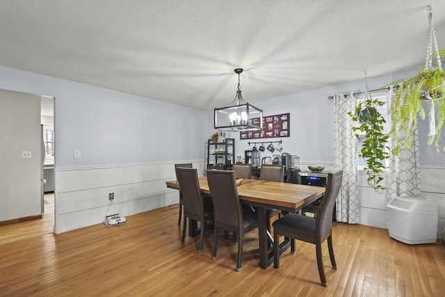 dining area featuring light wood-type flooring, a textured ceiling, a wealth of natural light, and an inviting chandelier