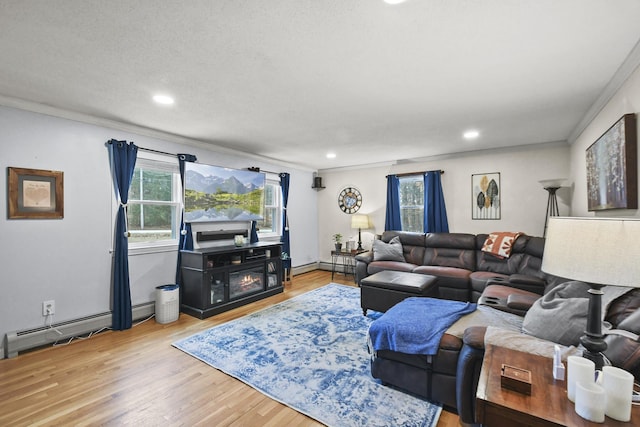 living room with baseboard heating, crown molding, plenty of natural light, and light hardwood / wood-style floors