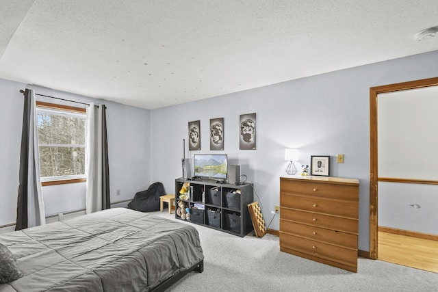 bedroom featuring a textured ceiling, light carpet, and a baseboard radiator