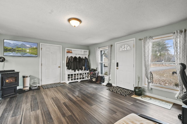 entrance foyer featuring a textured ceiling, a wood stove, and dark wood-type flooring