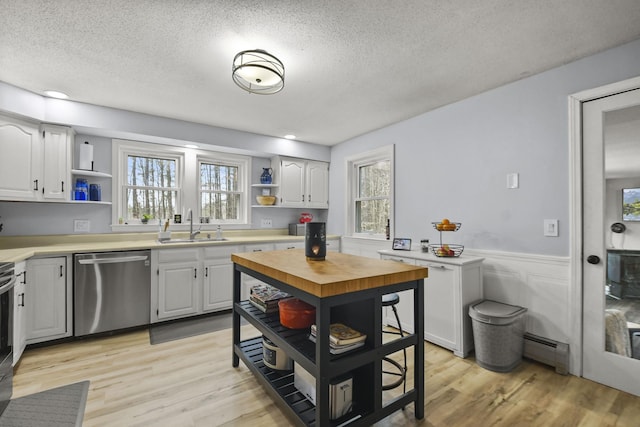 kitchen featuring stainless steel dishwasher, white cabinetry, sink, and a baseboard heating unit