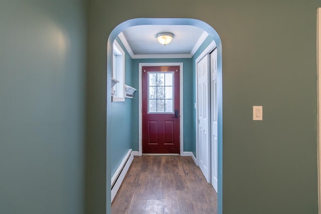 doorway featuring dark wood-type flooring, crown molding, and a baseboard heating unit