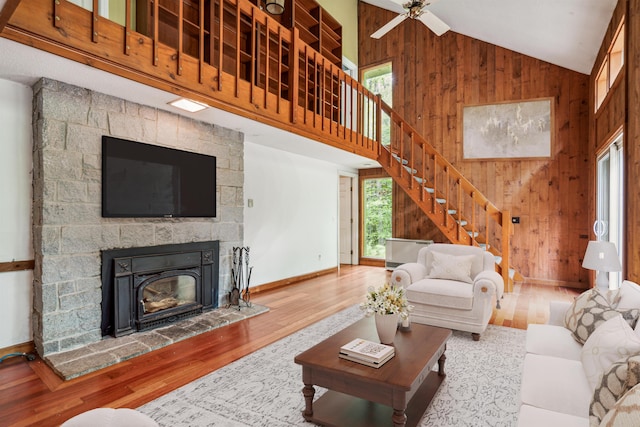 living room with high vaulted ceiling, ceiling fan, and wooden walls