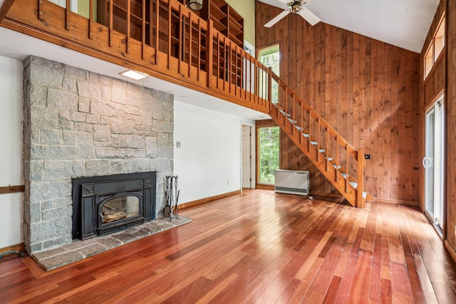 unfurnished living room featuring wooden walls, ceiling fan, a fireplace, and high vaulted ceiling