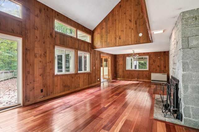 unfurnished living room featuring a fireplace, wood-type flooring, a textured ceiling, and wood walls