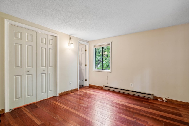 unfurnished bedroom with hardwood / wood-style flooring, a closet, a textured ceiling, and a baseboard heating unit