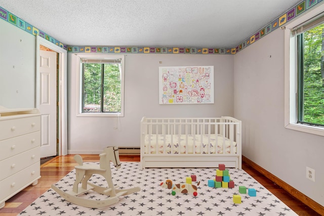 bedroom with wood-type flooring, a textured ceiling, and a nursery area