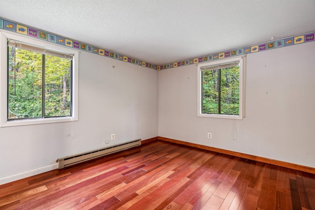 spare room featuring hardwood / wood-style flooring, plenty of natural light, a textured ceiling, and a baseboard radiator