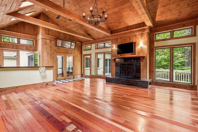 unfurnished living room with beam ceiling, wood walls, and high vaulted ceiling