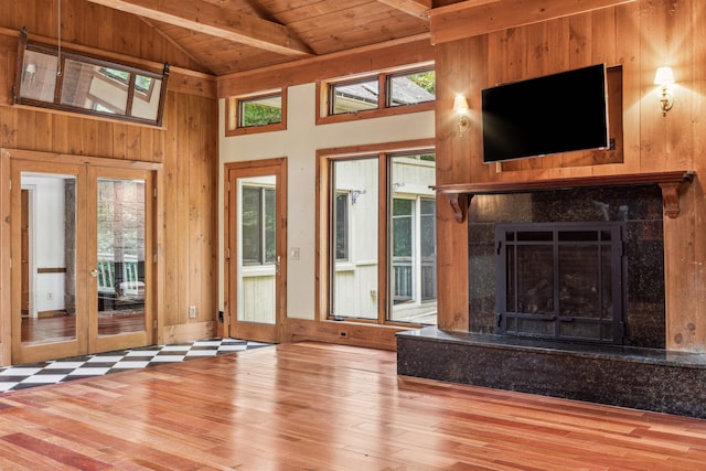 unfurnished living room featuring hardwood / wood-style floors, wooden ceiling, french doors, and wooden walls