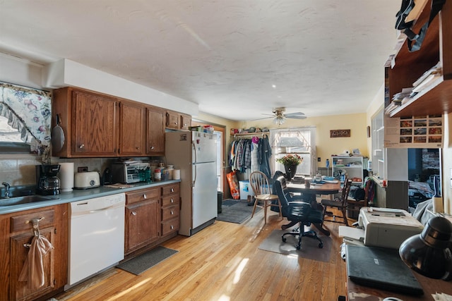 kitchen featuring white appliances, backsplash, sink, ceiling fan, and light wood-type flooring