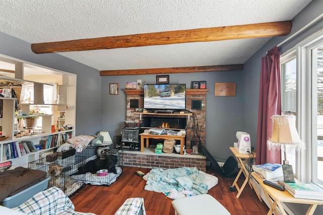 living room featuring beamed ceiling, wood-type flooring, a textured ceiling, and a brick fireplace