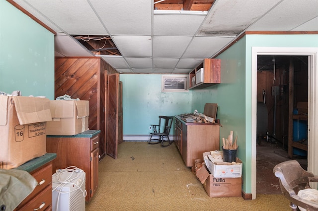 basement featuring baseboard heating, a drop ceiling, and wooden walls