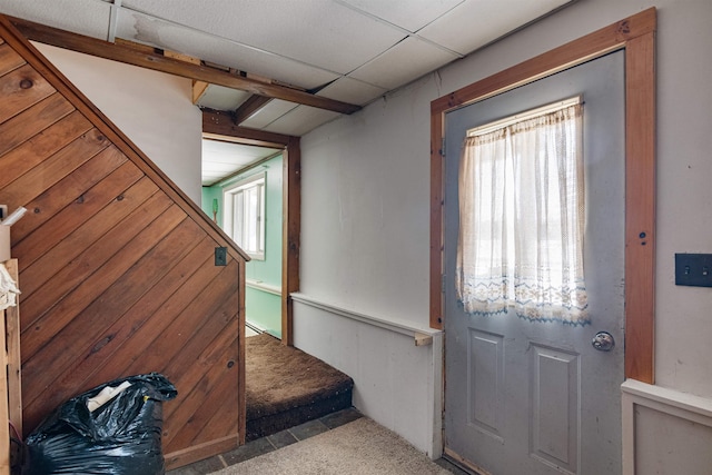 doorway to outside featuring wood walls and light carpet