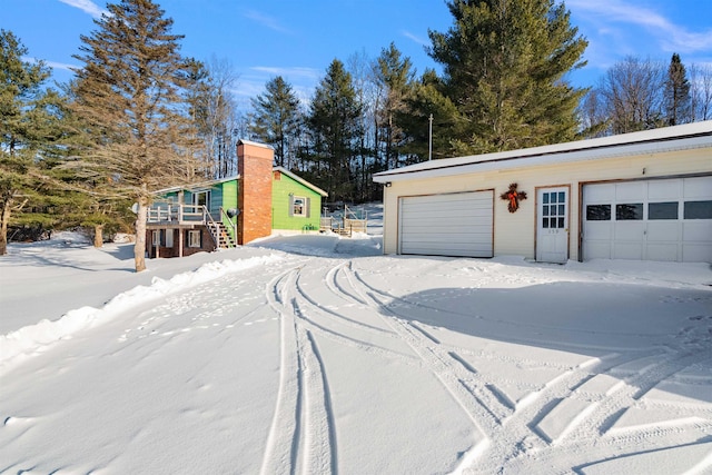 snow covered garage with a detached garage