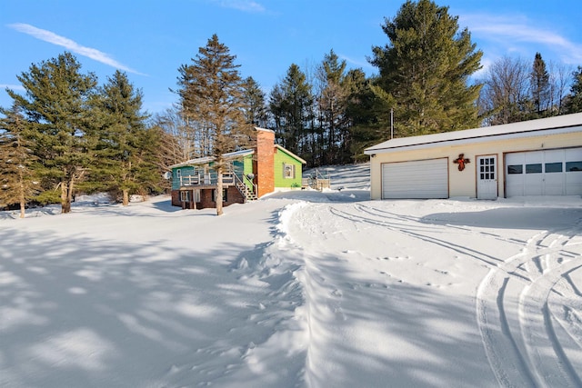 snowy yard with a garage and an outdoor structure