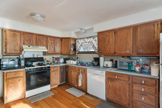 kitchen featuring white dishwasher, a sink, gas range oven, under cabinet range hood, and black microwave