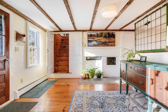 interior space with beam ceiling, a baseboard radiator, a healthy amount of sunlight, and light hardwood / wood-style floors