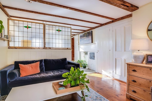 living room featuring beamed ceiling, hardwood / wood-style flooring, and wooden walls