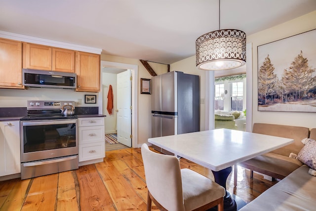 kitchen with appliances with stainless steel finishes, decorative light fixtures, and light hardwood / wood-style floors