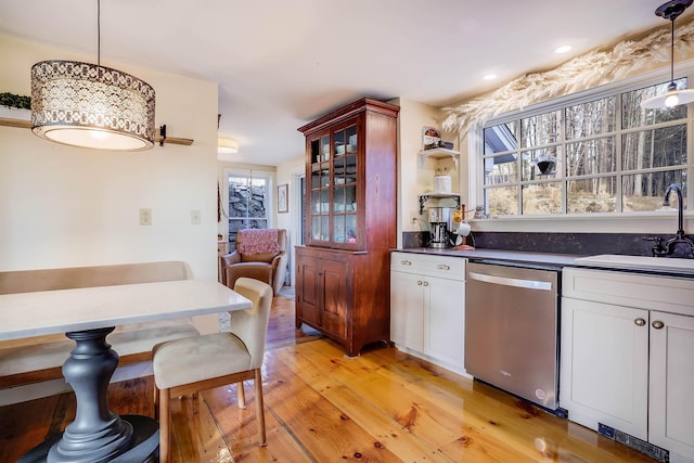 kitchen featuring sink, a healthy amount of sunlight, light hardwood / wood-style flooring, stainless steel dishwasher, and decorative light fixtures