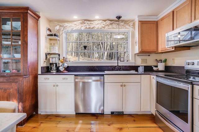 kitchen with pendant lighting, white cabinets, sink, light wood-type flooring, and appliances with stainless steel finishes