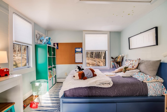 bedroom with wood-type flooring and a baseboard heating unit