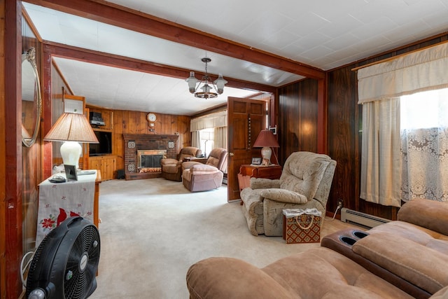 carpeted living room with beam ceiling, baseboard heating, a chandelier, wooden walls, and a fireplace